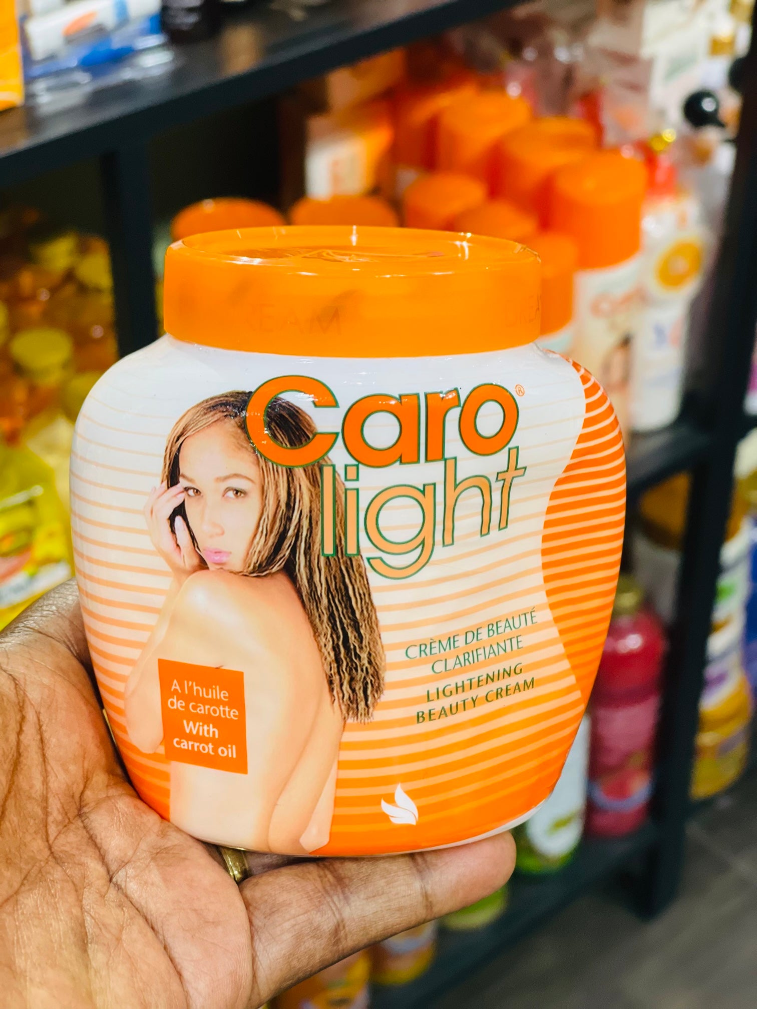 Hand holding a jar of Caro Light cream with a blurred store shelf in the background