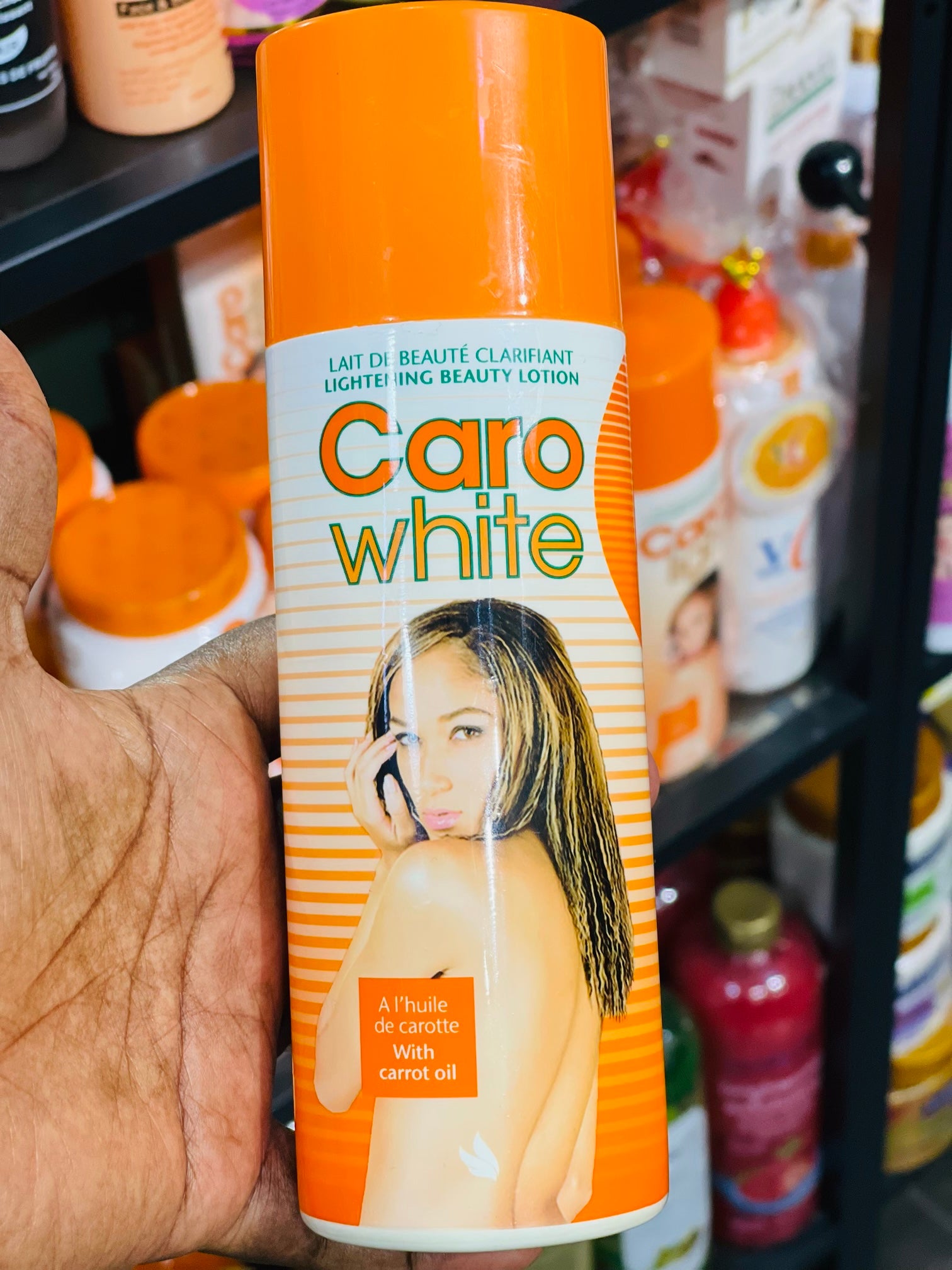 Caro White lotion bottle held by a hand with a blurred store shelf background